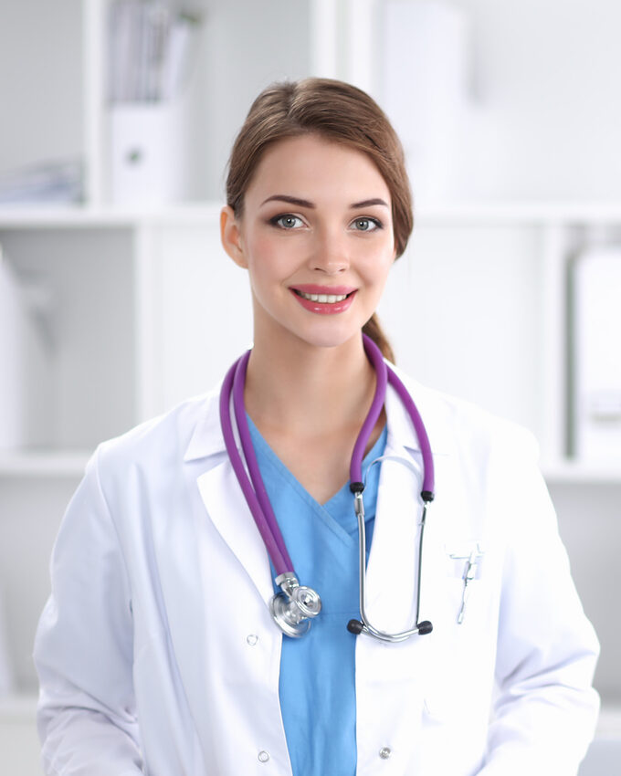 Portrait of young woman doctor with white coat standing